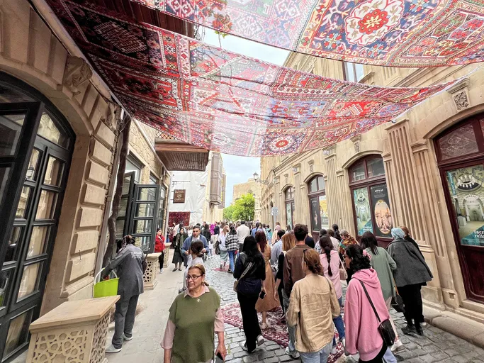 Streets of the old city of Baku, with tourists and a canopy made of woven carpets, Azerbaijan. Many people and tourists strolling around.